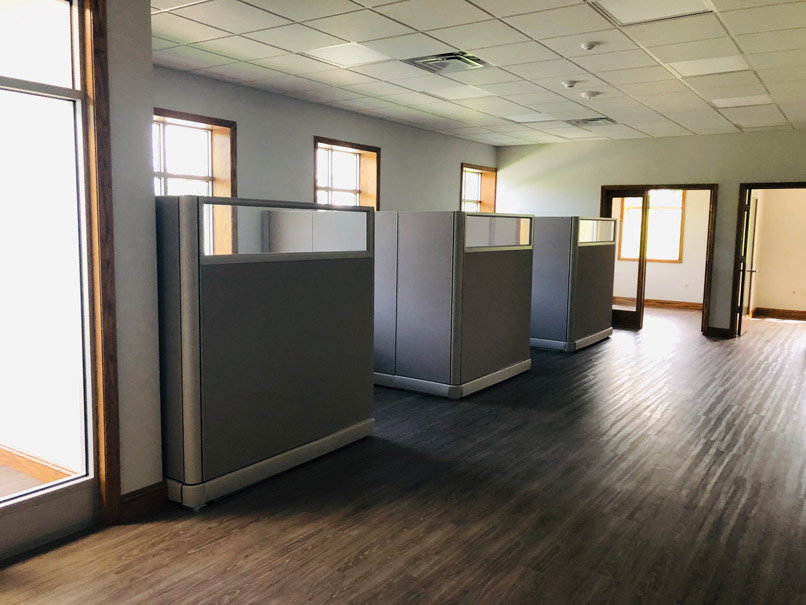 Three cubicles in an open office with hardwood floors